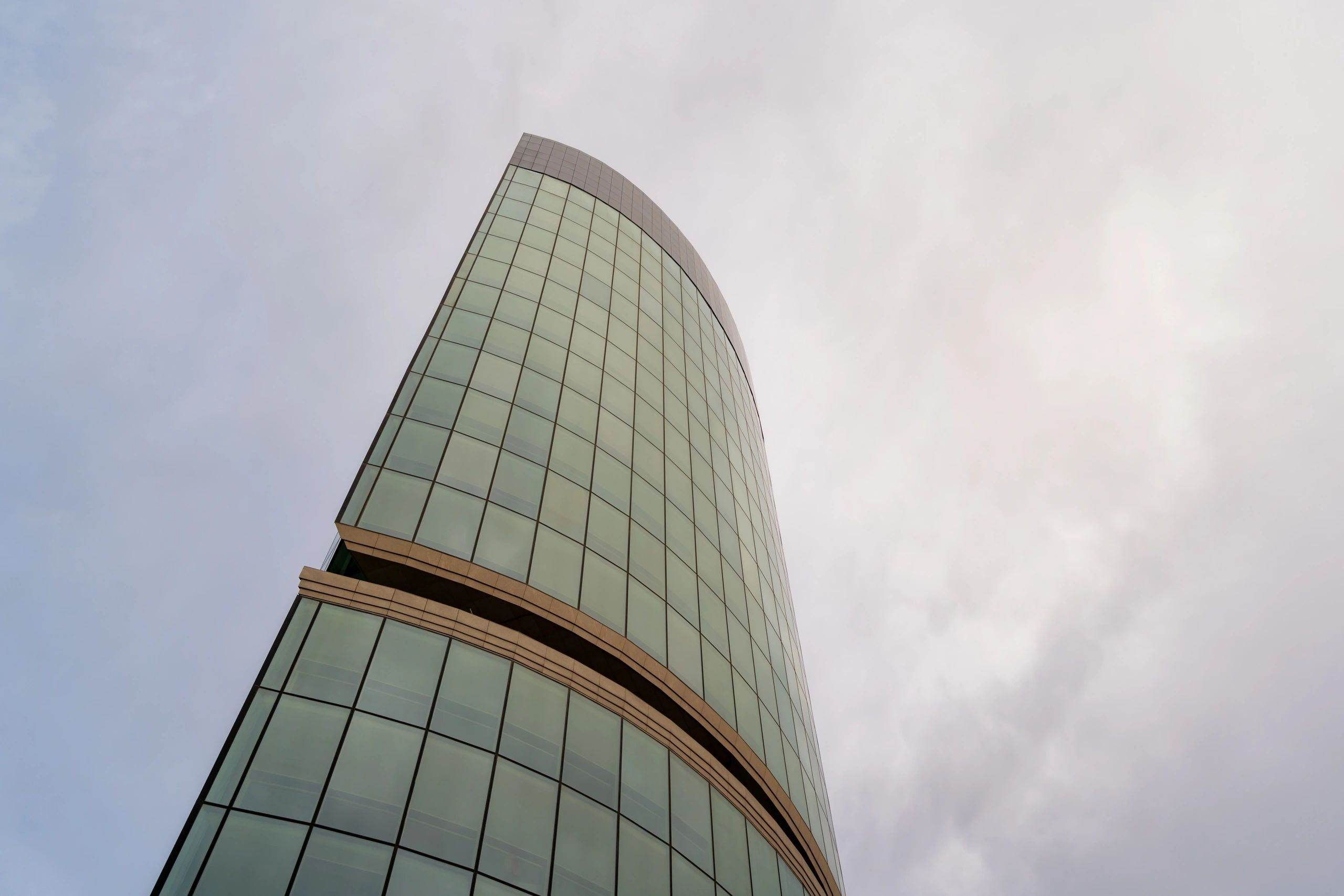 Modern glass skyscraper building against cloudy sky